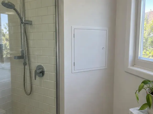 Bathroom shower wall with a small white access panel and tiled wet area in Lane Cove